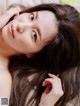 A woman with long brown hair laying on a bed.