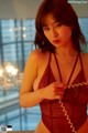 A woman in a red lingerie holding a phone.