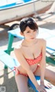 A woman in a red and white polka dot bikini sitting on a bench.