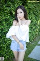 A woman in a white top and denim shorts posing for a picture.