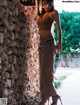 A woman standing in front of a stone wall.