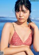 A woman in a red and white bikini standing on a beach.