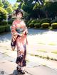 A woman in a kimono standing on a sidewalk.