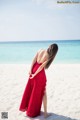 A woman in a red dress standing on a beach.