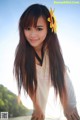 A woman with long brown hair and a sunflower in her hair.