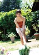 A woman is playing with a watermelon in the yard.