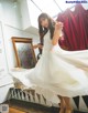 A woman in a white dress standing in front of a mirror.